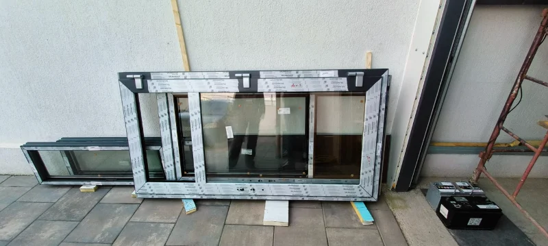 Windows with anthracite frames, still protected by film, placed on a terrace before installation