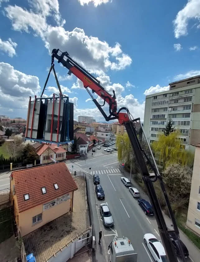 A crane lifting a large package above a street
