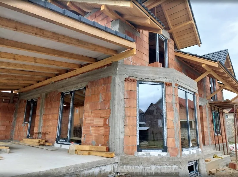 Ferestre și uși cu ramă antracit către o terasă, la o casă în construcție