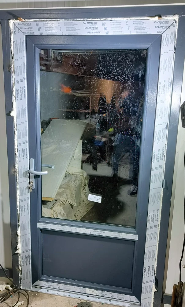Anthracite door with a large glass pane, still protected by film, during installation