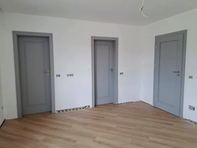 Three grey interior doors with a classic panel, in a room with parquet flooring