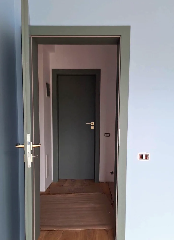 Grey interior doors in a hallway, one with a vertical slot of black glass