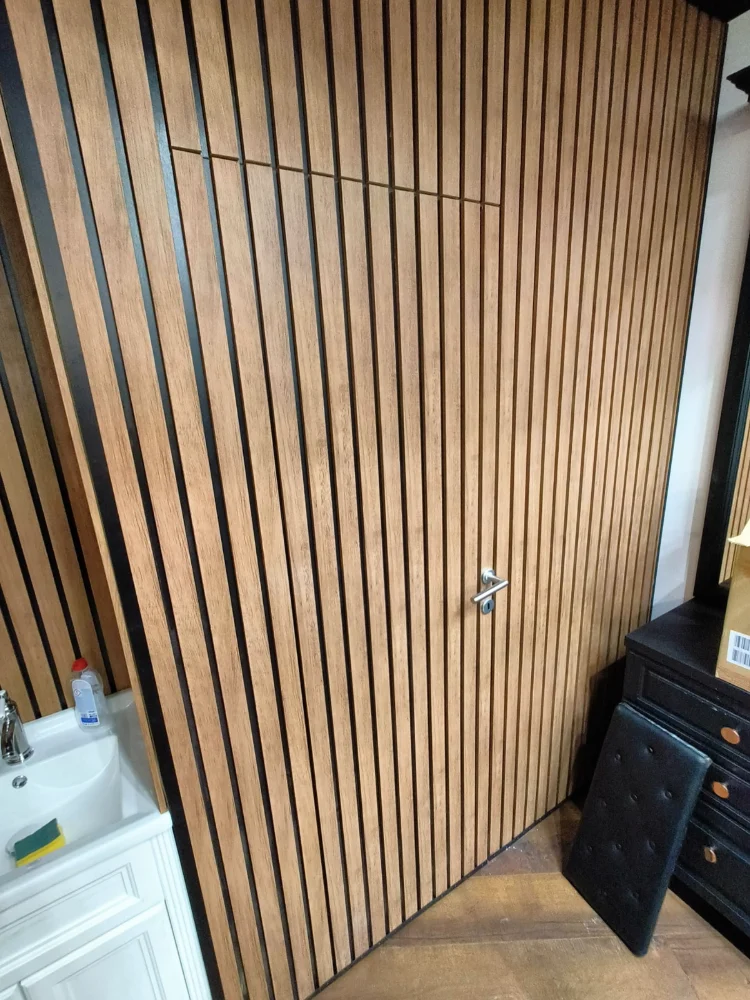 Door covered with vertical wooden slats, in a room with parquet flooring
