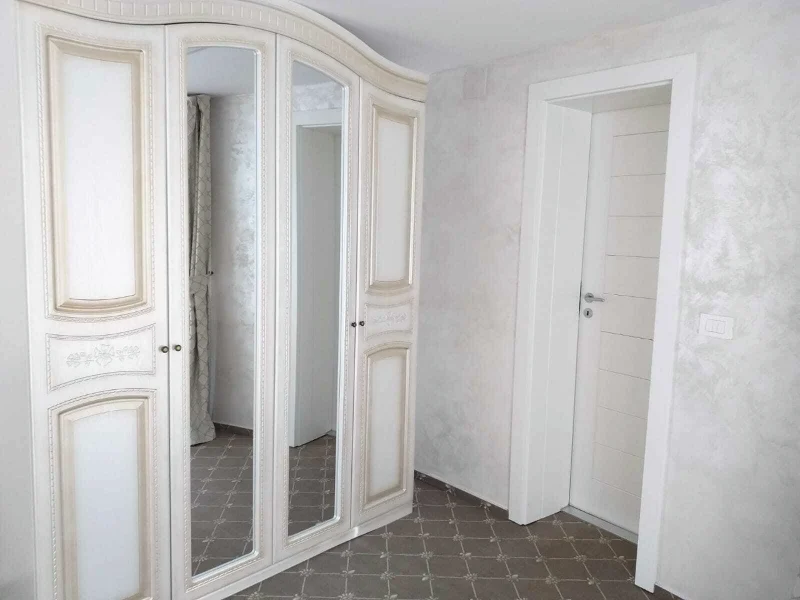 Solid white MDF interior door, next to a mirrored wardrobe